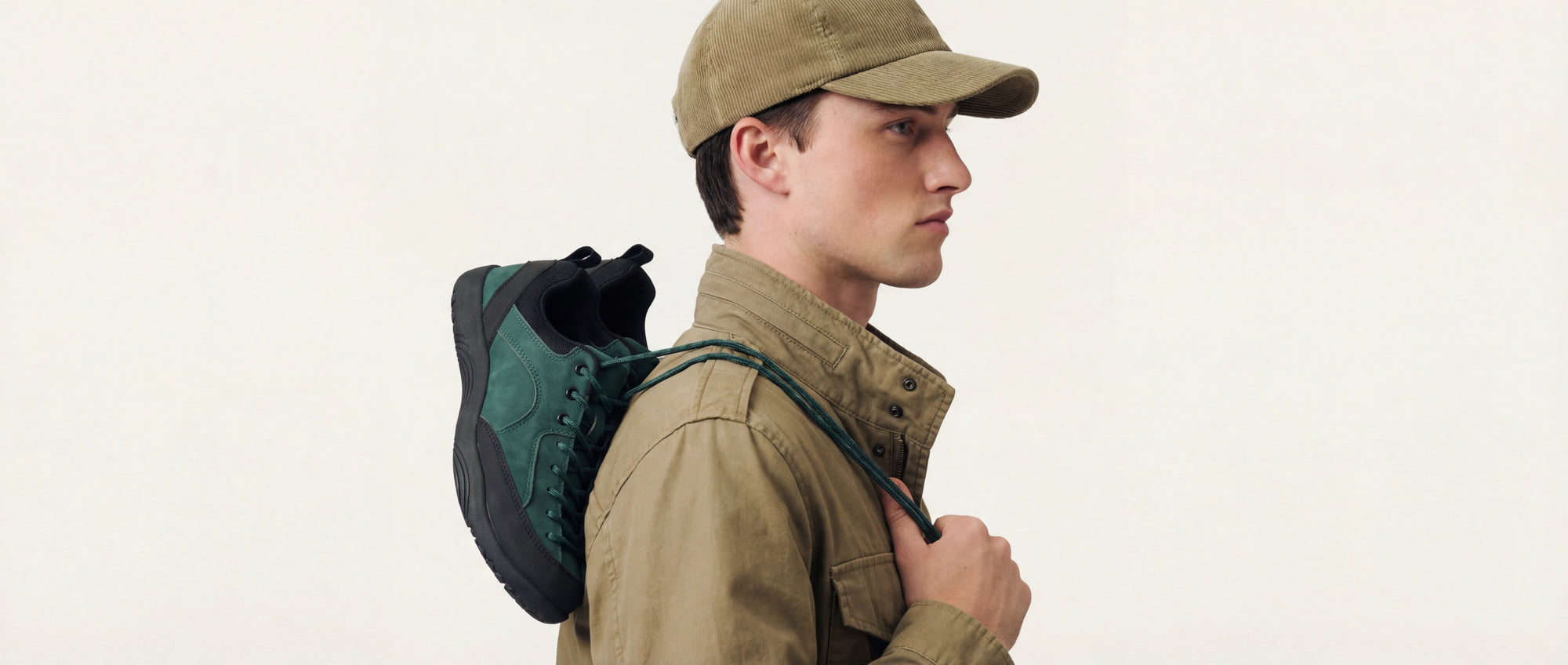 side view of a model holding a green outdoor sneaker over the shoulder